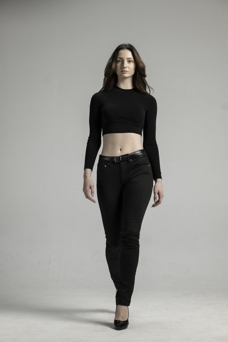 a woman in black pants and crop top posing for a photo with her hands on her hips