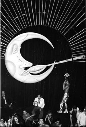 an old black and white photo of people in front of a large object that looks like the moon