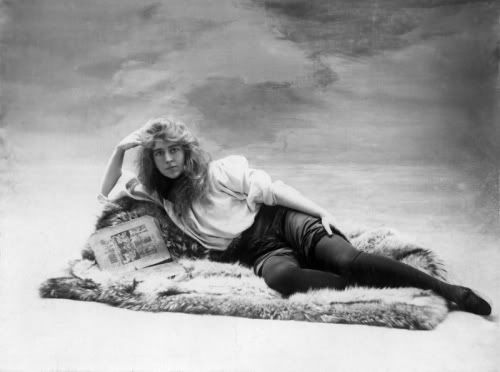 black and white photograph of a woman laying on a fur rug with her legs crossed