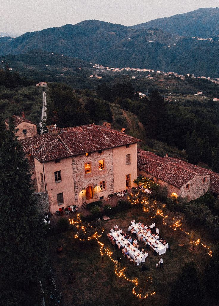 an aerial view of a house with lights on the lawn and tables set up outside