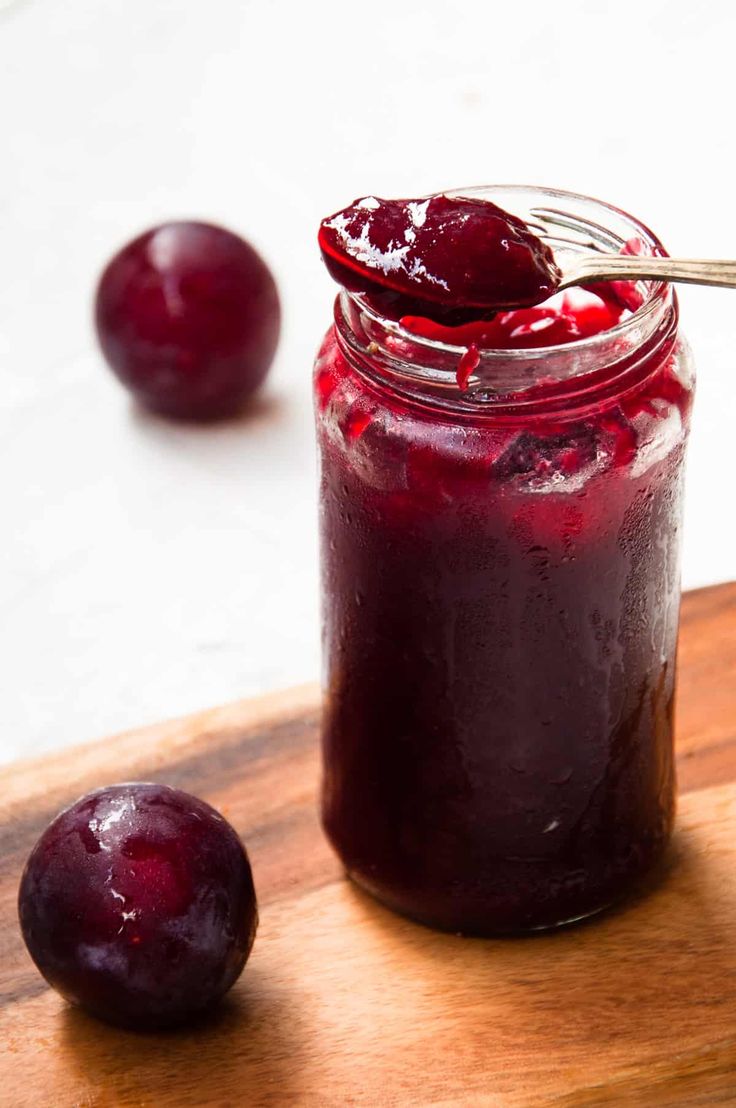 a glass jar filled with cherries on top of a wooden cutting board