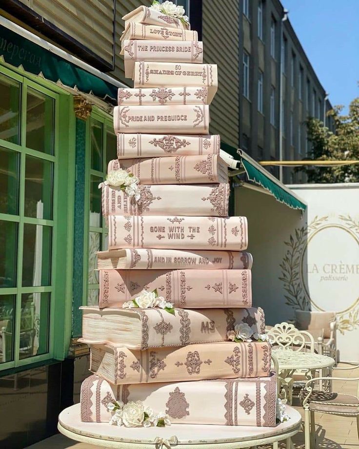 a tall stack of books sitting on top of a table next to a green building