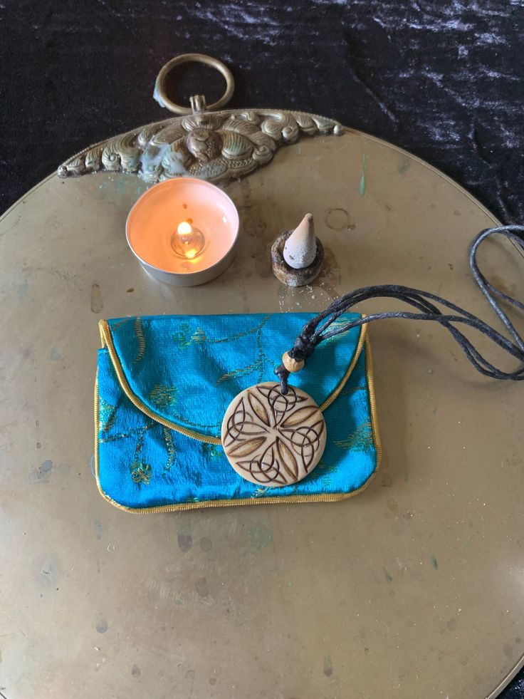 a blue purse sitting on top of a table next to a candle and some other items