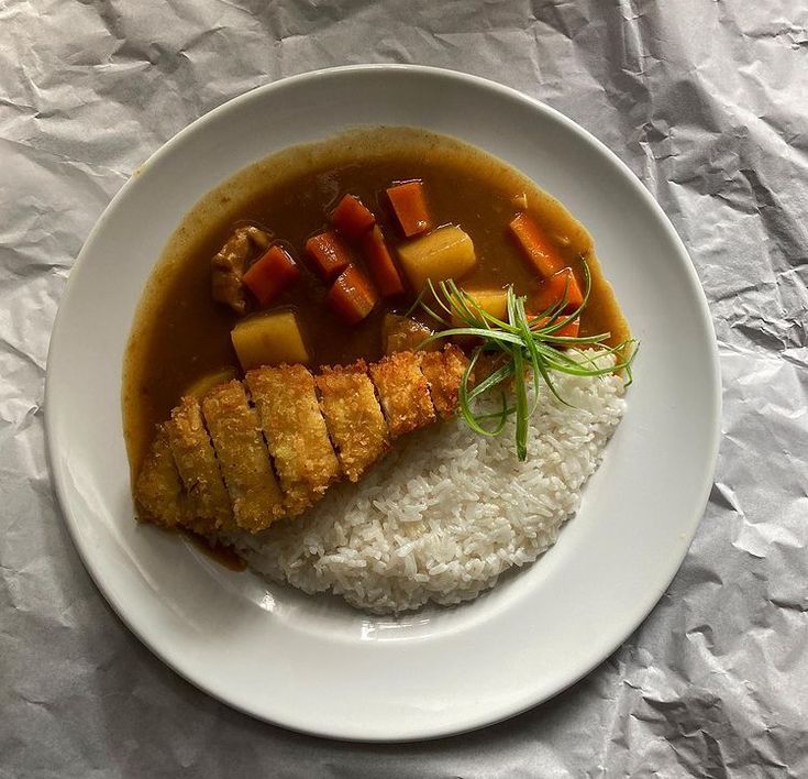 a white plate topped with rice and meat covered in gravy