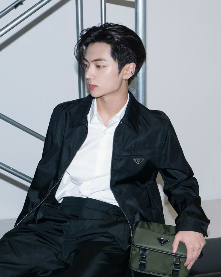 a young man sitting on top of a chair holding a green bag