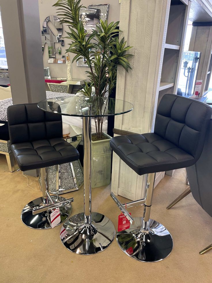 two black chairs and a table in a room with mirrors on the wall behind them