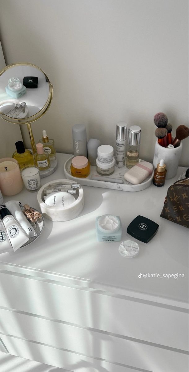 a white dresser topped with lots of cosmetics and personal care items next to a mirror