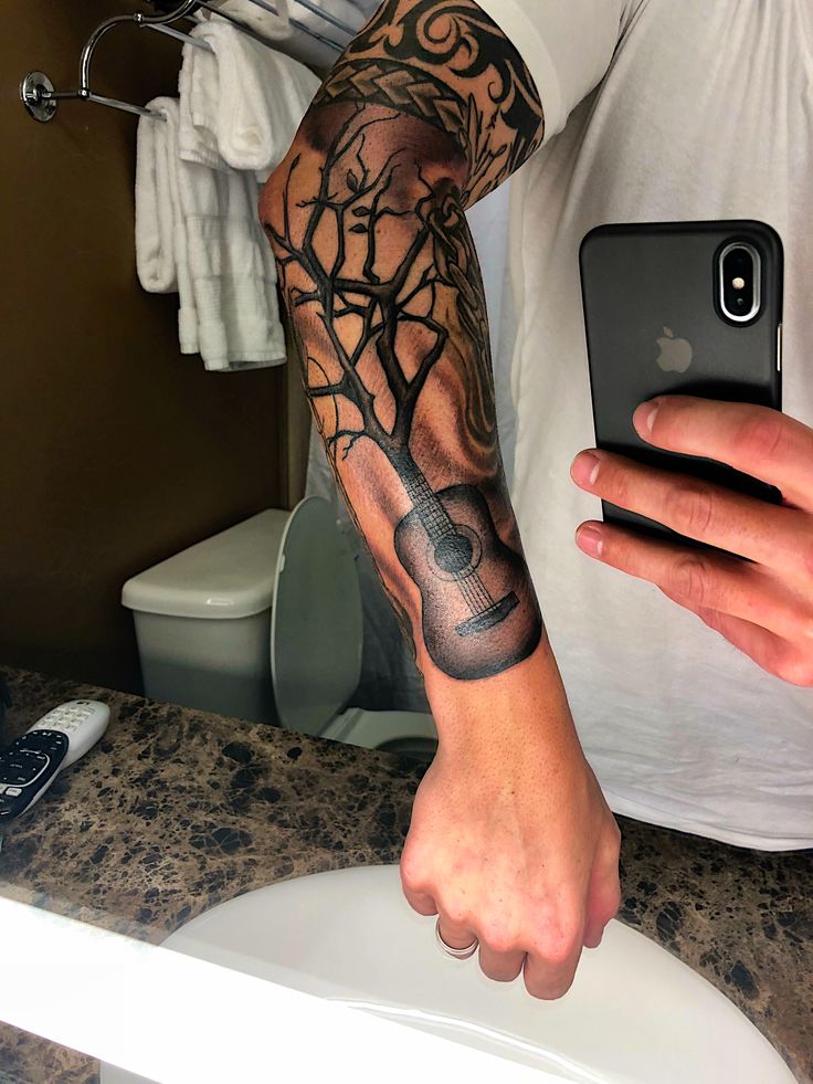 a man with a tattoo on his arm holding a cell phone