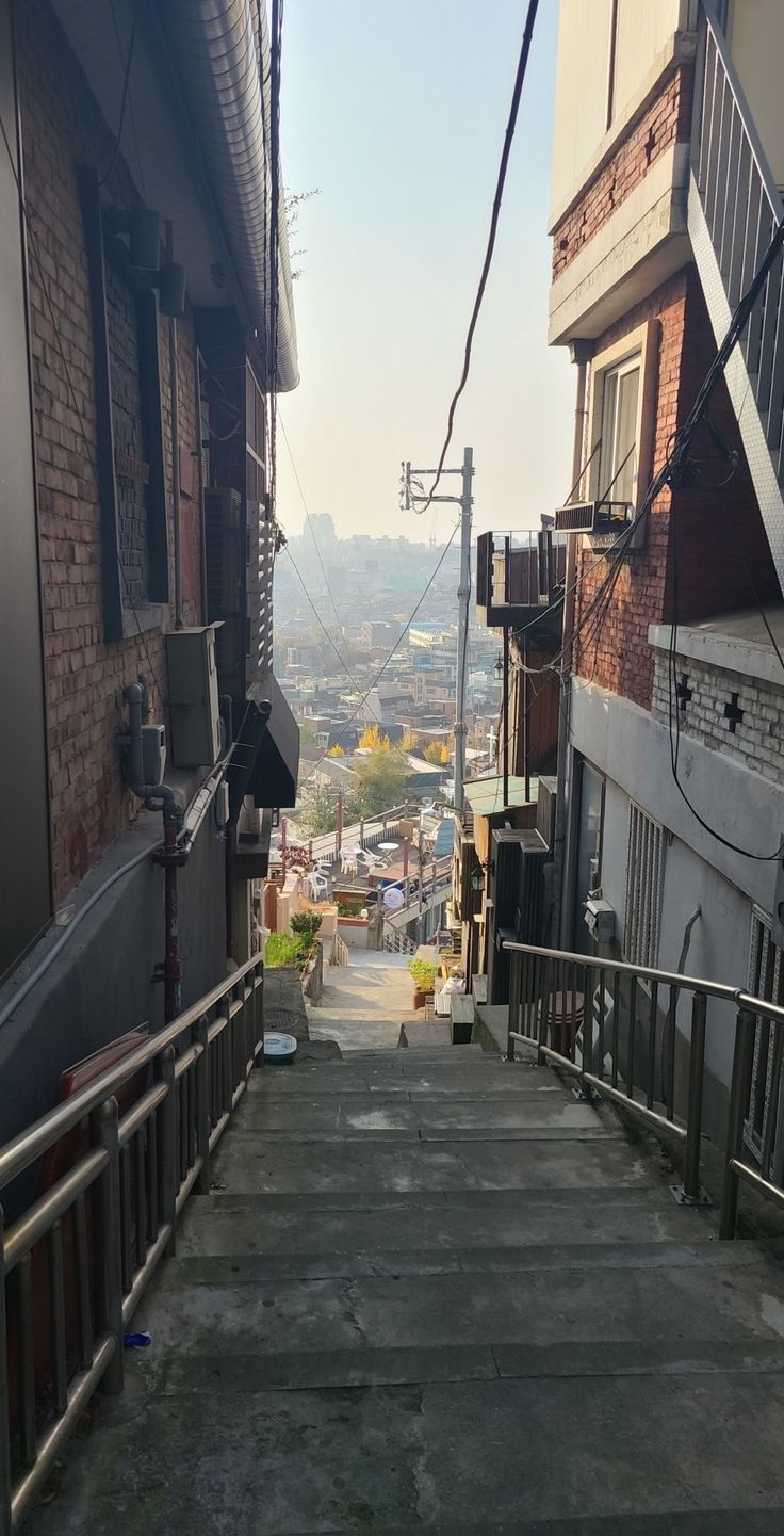 an alleyway with stairs leading up to the top floor and buildings in the background