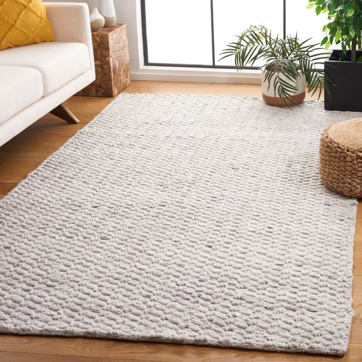 a living room with a white rug and potted plant on the floor next to it