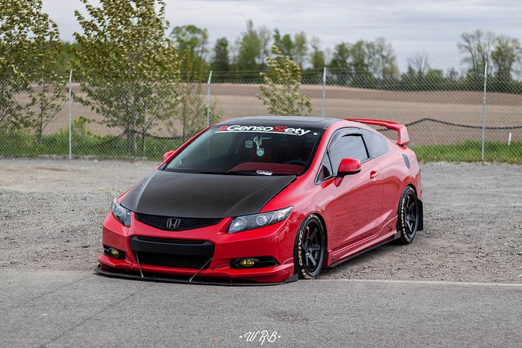 a red car parked in a parking lot next to a fence