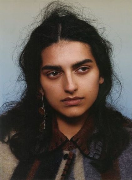 a young man with long hair and large earrings on his head looking at the camera