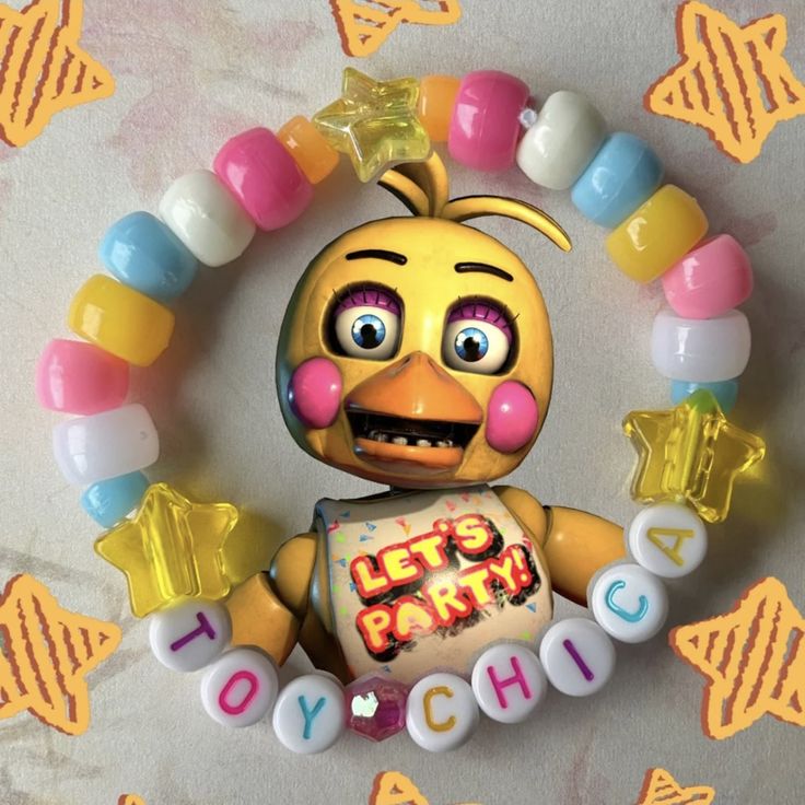 the toy chick is holding candy in her hands and wearing a necklace with letters on it