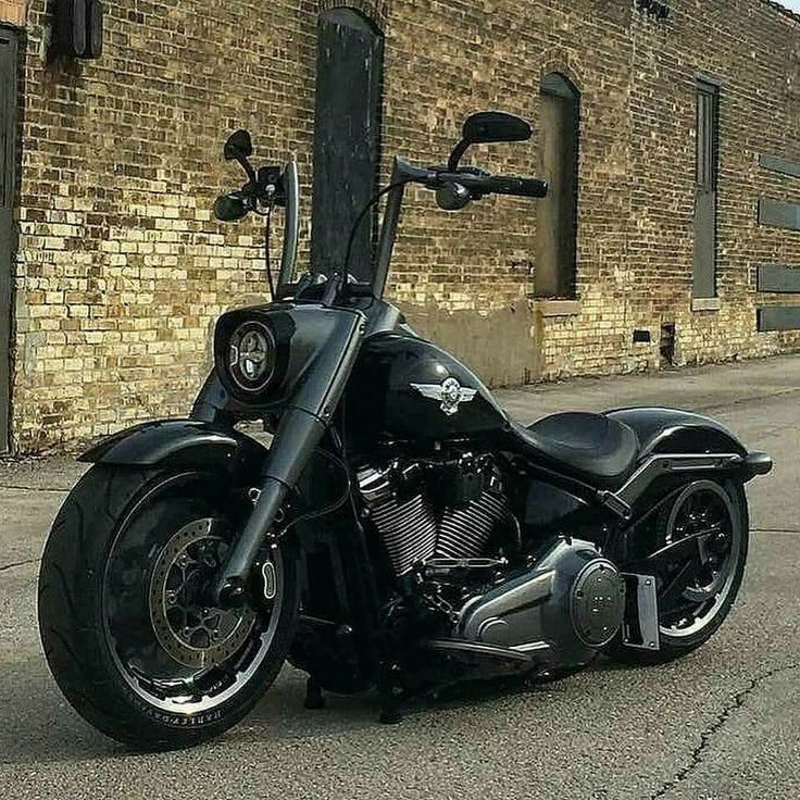 a black and white photo of a motorcycle parked in front of a brick building