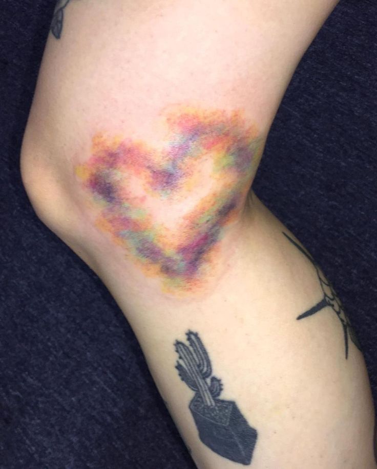 a woman with tattoos on her leg and arm is covered in colored powder while holding a cell phone