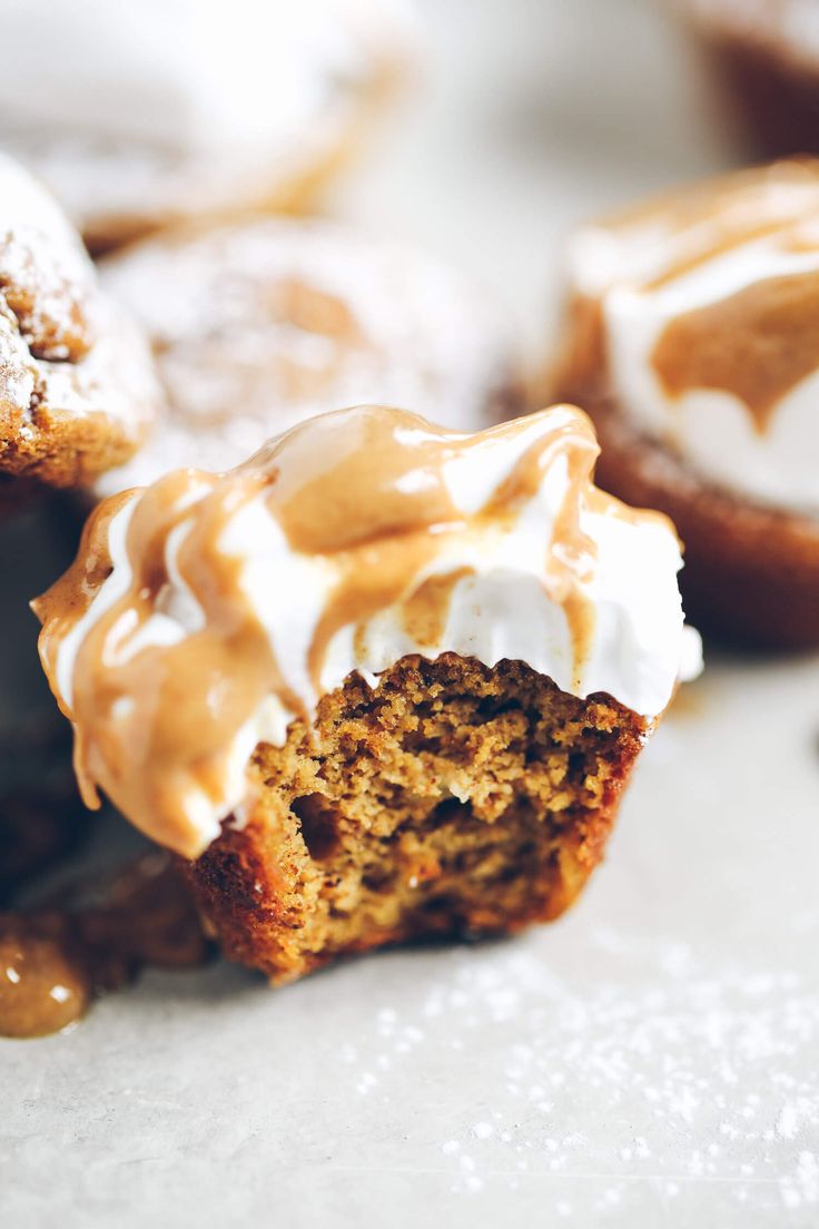 several cupcakes with white frosting and nuts are on a wooden table next to each other