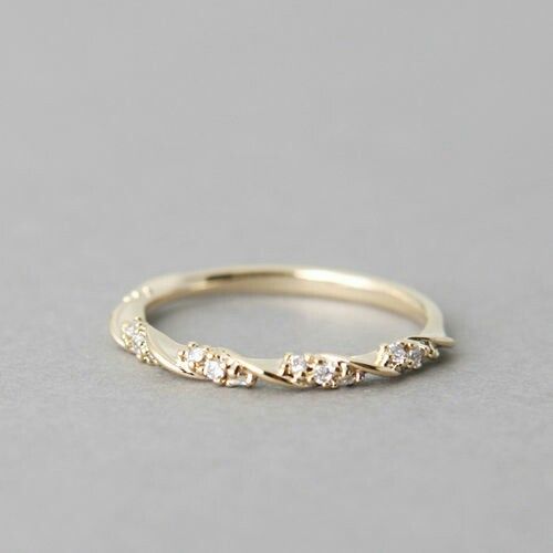 a yellow gold ring with five diamonds on it, sitting on a gray surface in front of the camera