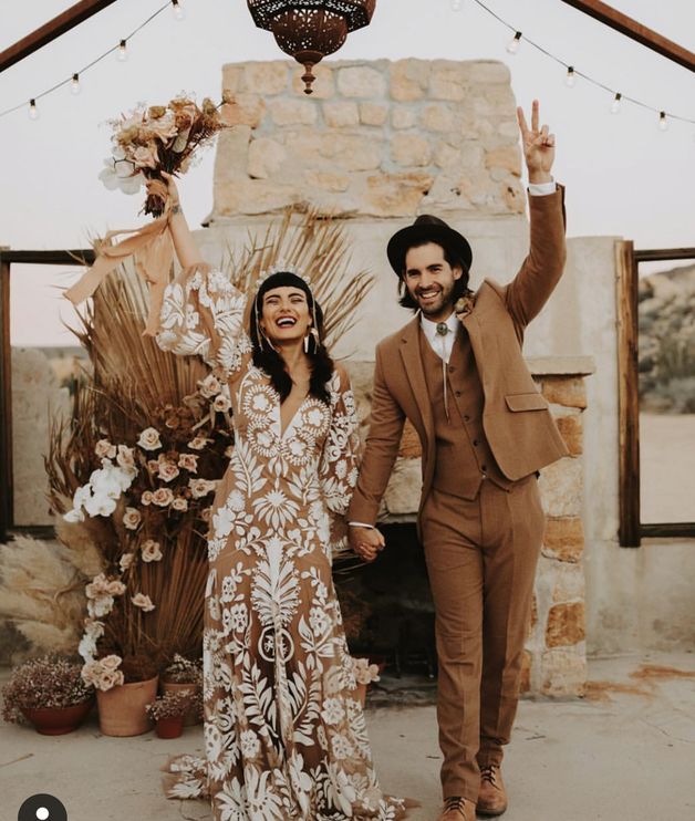 a man and woman standing next to each other in front of a stone fire place