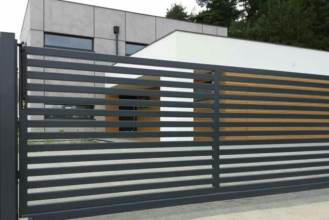 a large metal gate with wooden slats on it's sides and a building in the background