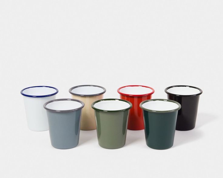 six different colored cups sitting next to each other on a white surface with one empty cup in the middle