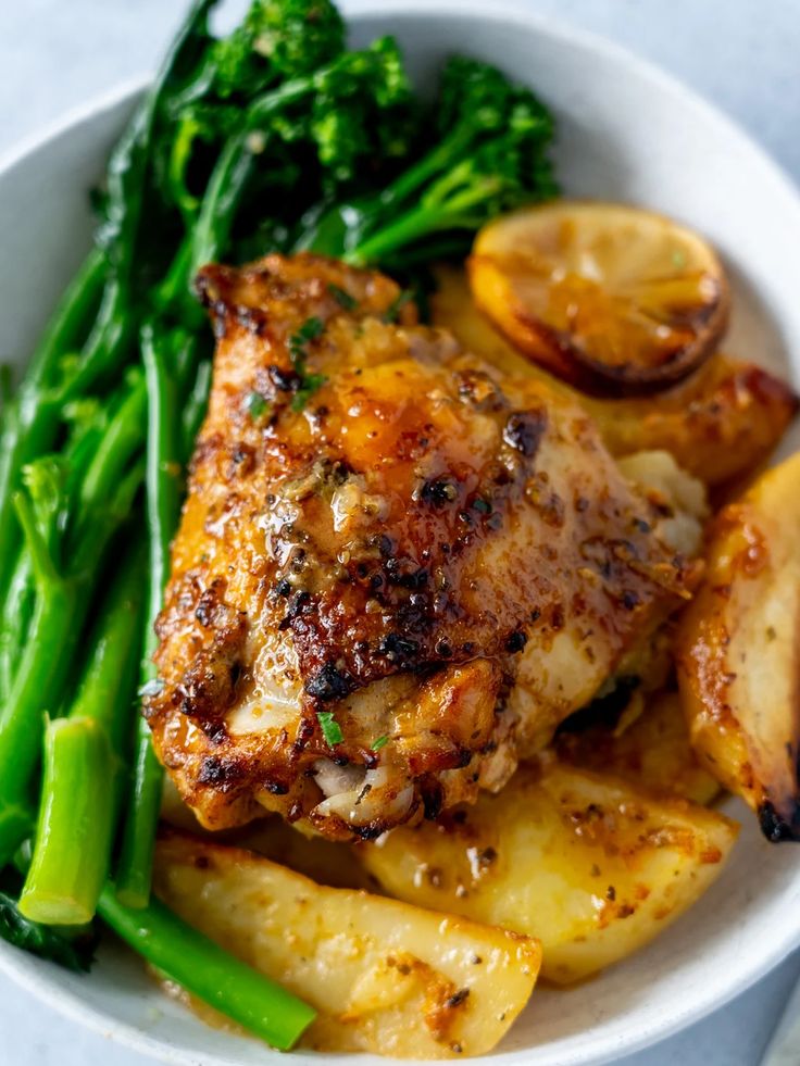 a white bowl filled with chicken, potatoes and green beans next to broccoli