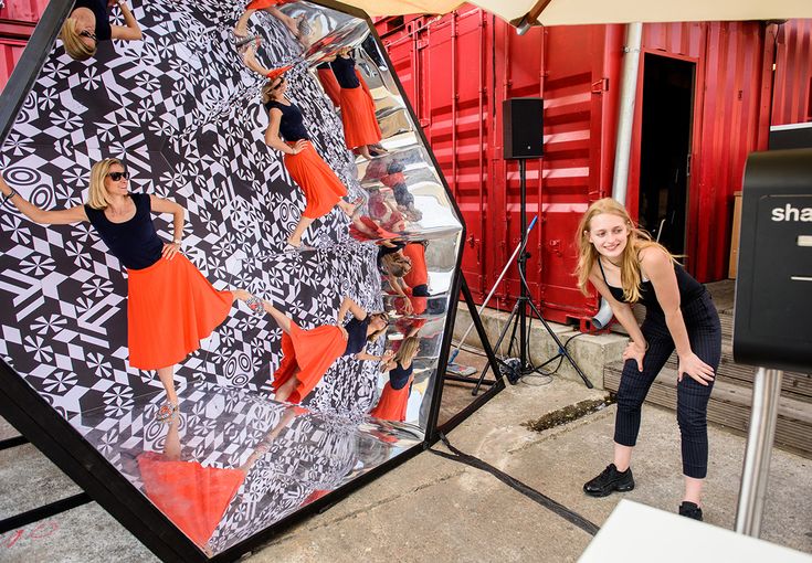 a woman standing in front of a giant display with people on it's sides