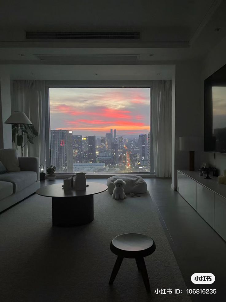 a living room filled with furniture and a view of the city at sunset or dawn