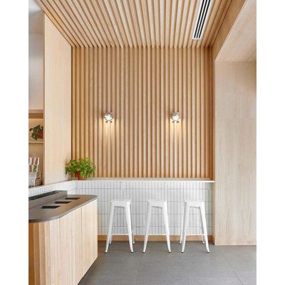 three white stools in front of a counter with two plants on top of it