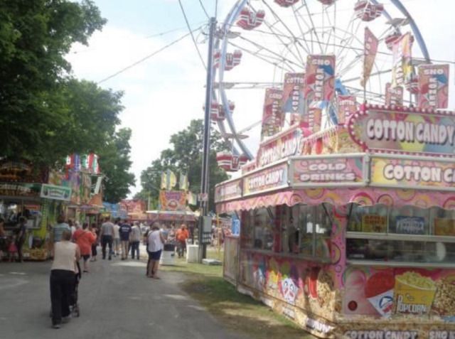 an amusement park filled with lots of rides and people walking down the road next to it