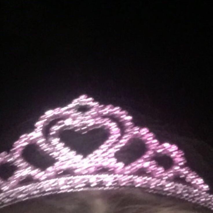 a woman wearing a tiara with pink lights on it's head in the dark