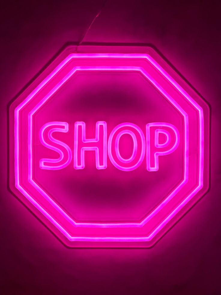 a neon sign with the word shop written on it in white letters, against a dark background