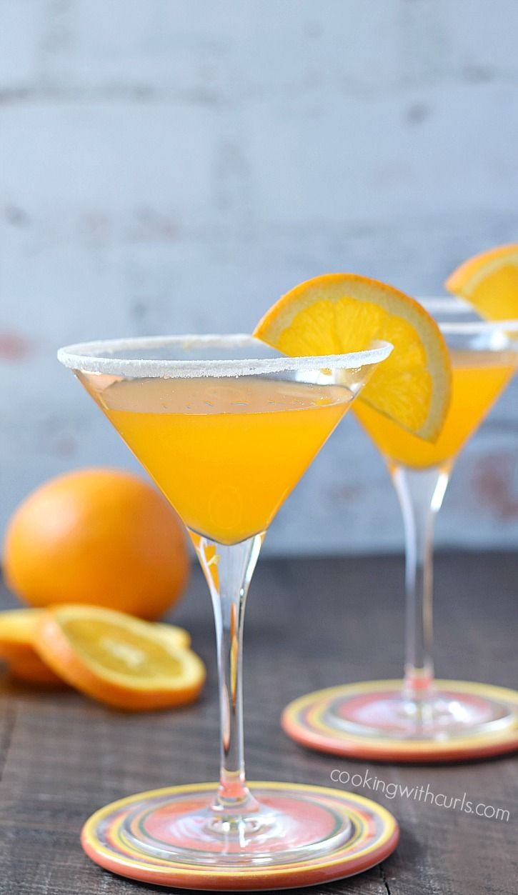 two glasses filled with orange juice and garnished with an orange slice on the rim