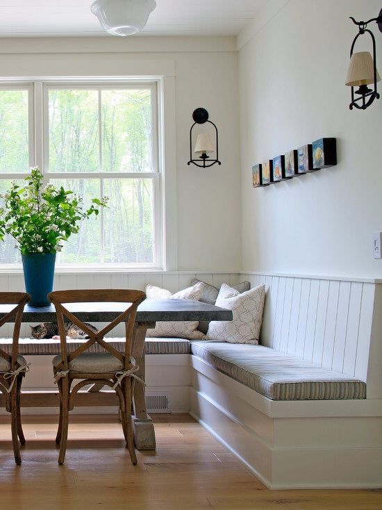 a dining room table with chairs and a bench in front of a window that overlooks the woods