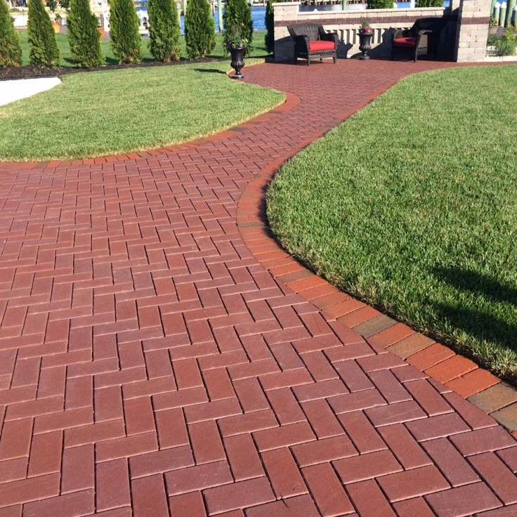 a red brick walkway in the middle of a grassy area