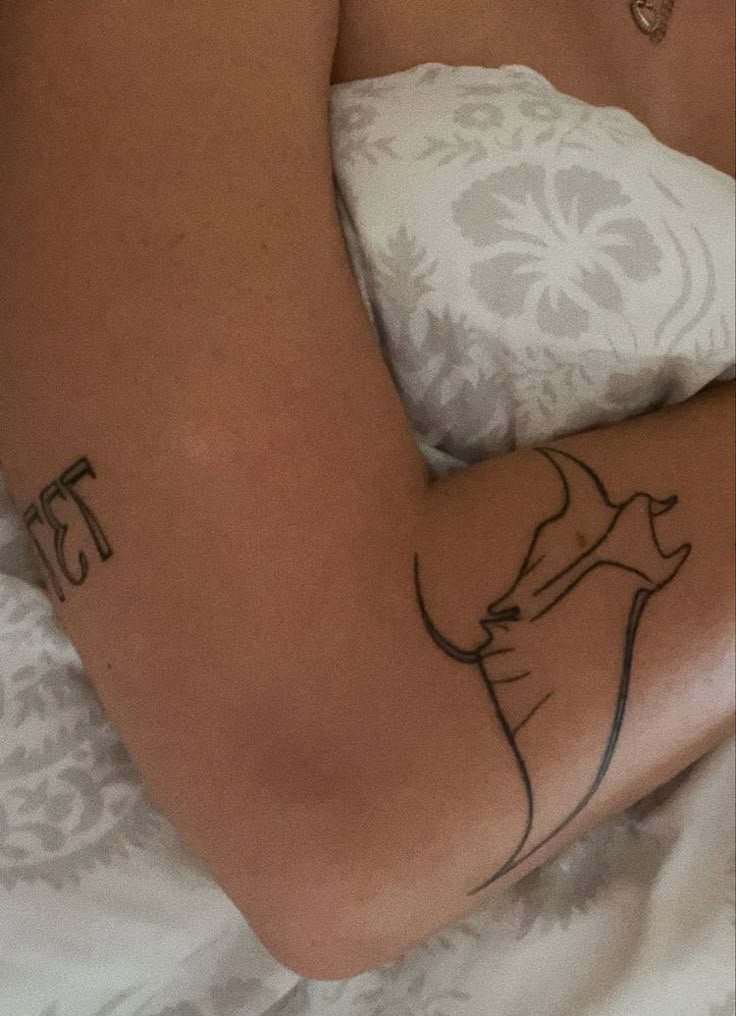 a woman laying in bed with a tattoo on her arm and the word ests