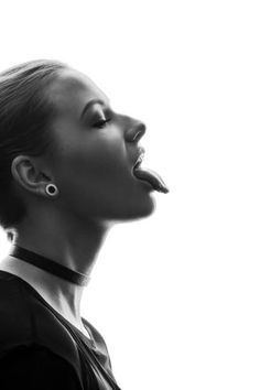 a black and white photo of a woman with her tongue out