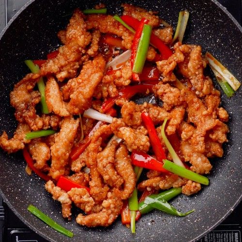 chicken and peppers are cooking in a wok