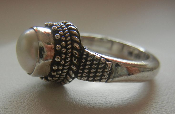 "Bali Suarti sterling silver and pearl ring. Small and beautiful, this ring has a soft iridescent white pearl, set in a raised bezel. The slightly domed pearl is encased in two rows of fine granulation pebbles and two rows of fine braiding. The sides have a striped-pebble vertical design. The back of the setting is solid and the band is thick. Beautifully made in the Balinese tradition and in excellent vintage condition. Please see detailed measurements below. > Size 5.5. *Thank you for doubl Silver Oval Pearl Ring For Anniversary, Sterling Silver Rings With Pearl Drop In Silver, Wedding Pearl Ring In Sterling Silver, Unique Silver Oval Pearl Ring, Silver Sterling Silver Ring With Pearl Drop, Silver Rings With Pearl Drop, Sterling Silver Rings With Pearl Drop, White Sterling Silver Rings With Pearl Drop, Wedding Pearl Ring Stamped 925 In Sterling Silver