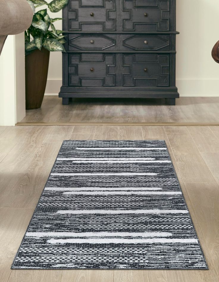 a black and white area rug on the floor in front of a dresser with drawers