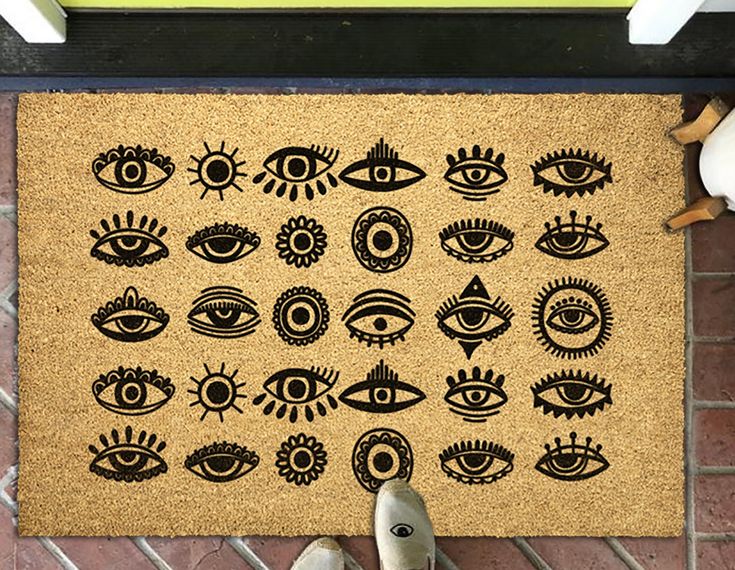 a door mat with an eye pattern on it and someone's feet standing next to it