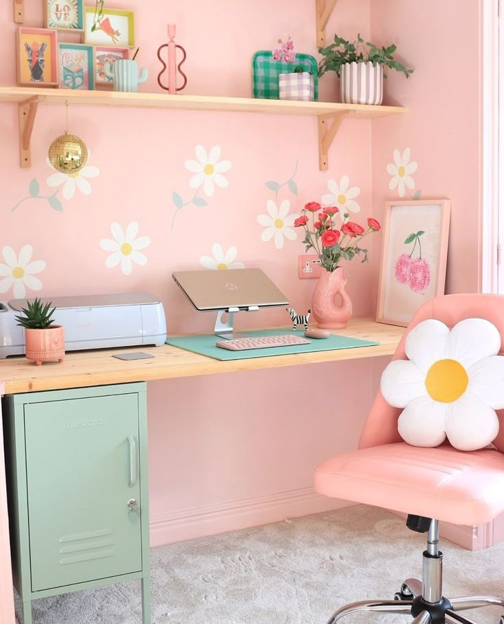 a pink desk and chair in a room with flower wallpaper on the walls behind it