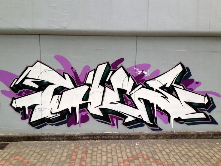 graffiti on the side of a building with purple and white spray painted letters above it