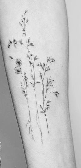 a black and white photo of a flower on the arm, with small flowers growing out of it