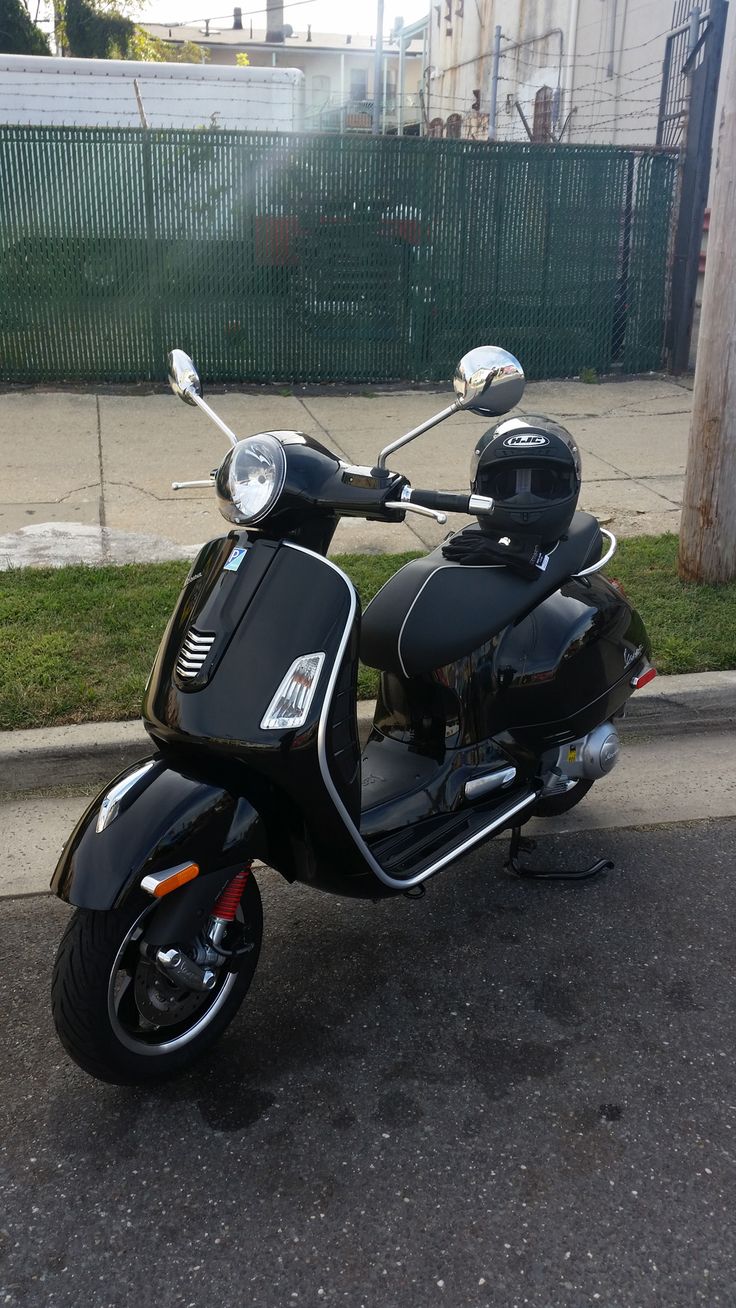 a motor scooter parked on the side of the road in front of a fence