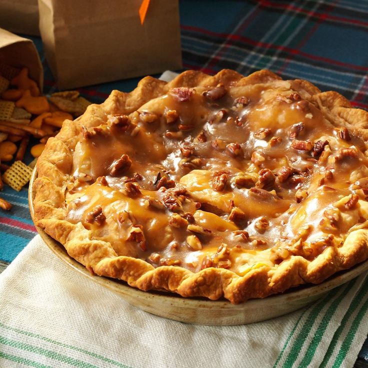 a pie sitting on top of a table next to crackers and a paper bag