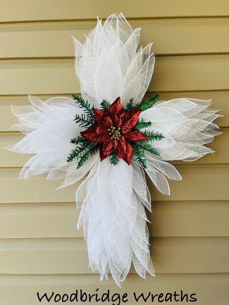 a white and red poinsettia wreath hanging on the side of a house