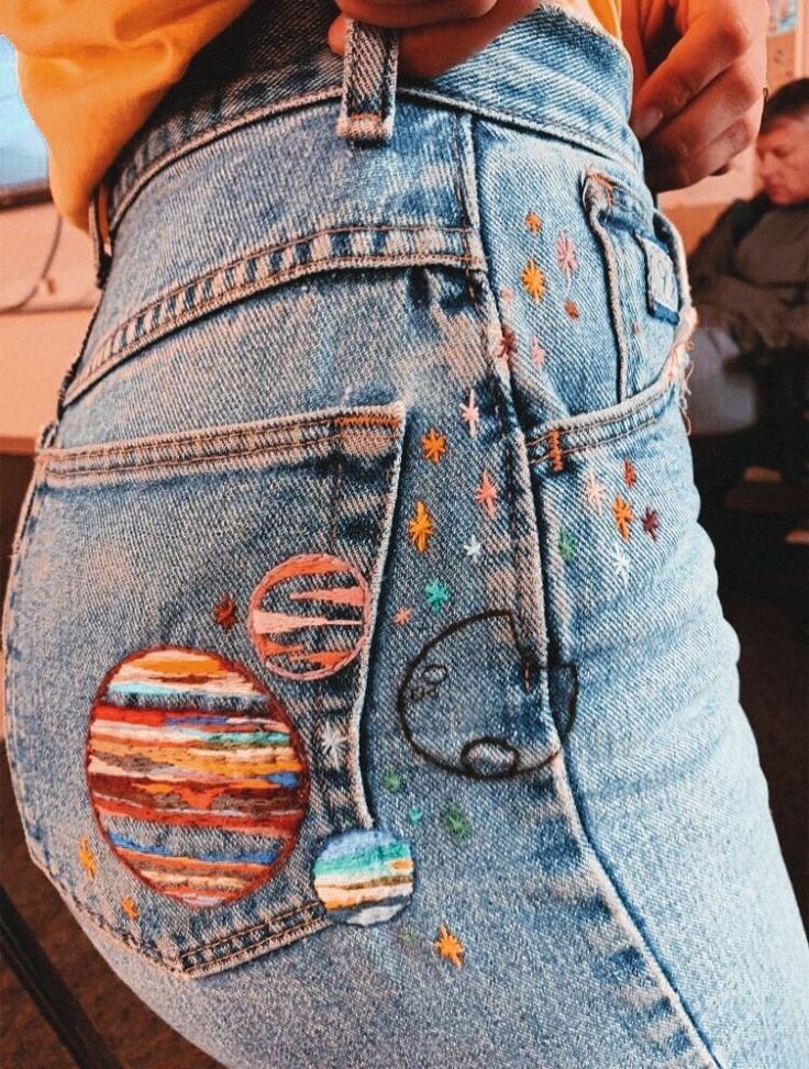 a woman's jeans with patches and planets on them