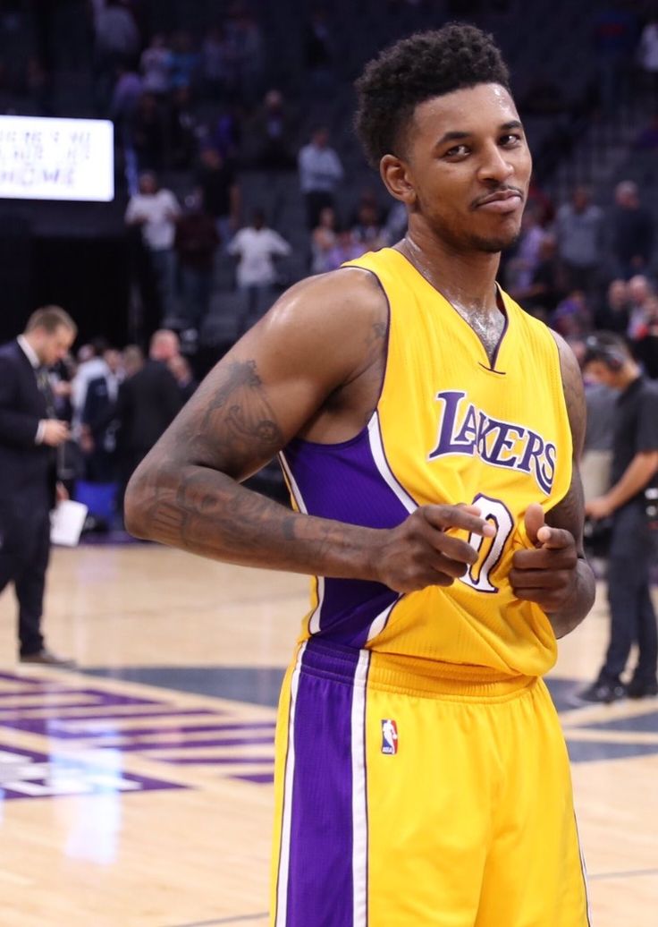 a man in a lakers uniform holding a basketball on his left hand and looking off to the side