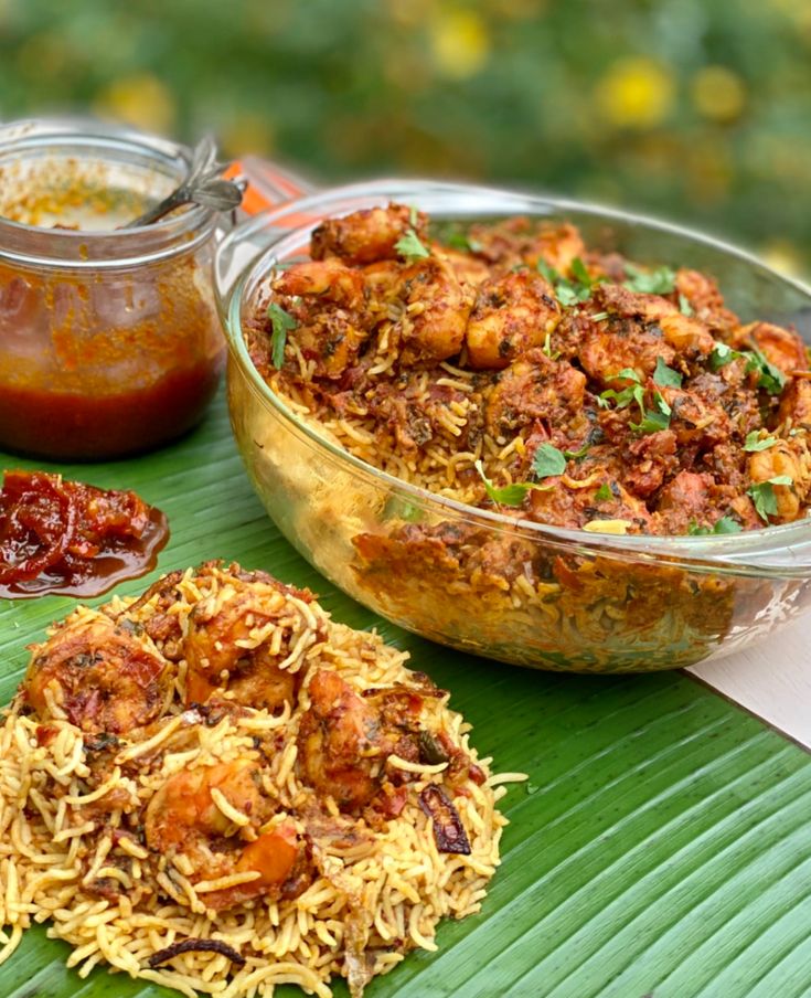 some food is sitting on top of a banana leaf next to other foods and condiments