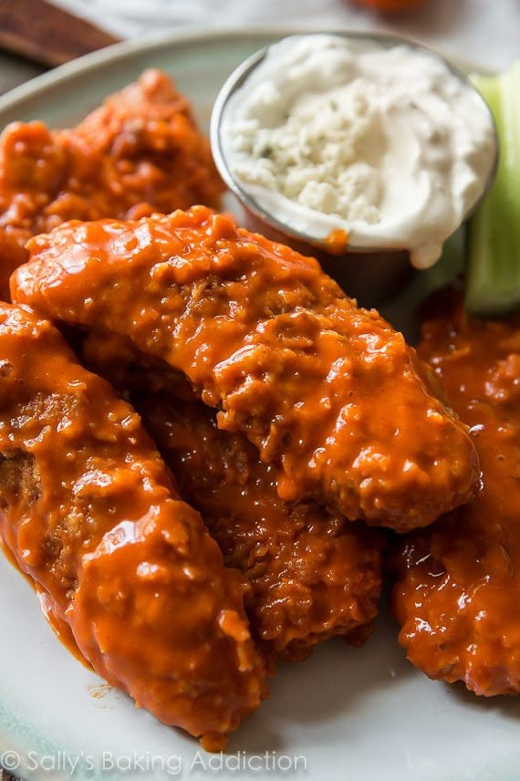 a white plate topped with chicken wings covered in sauce and garnished with celery